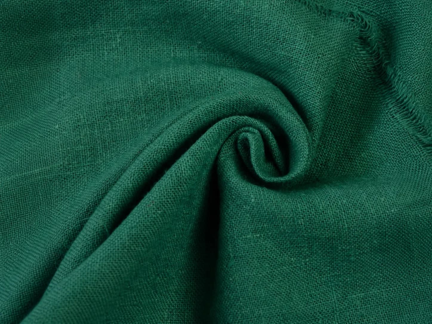 Close-up of deep teal khadi with a coarse handwoven texture and frayed edge